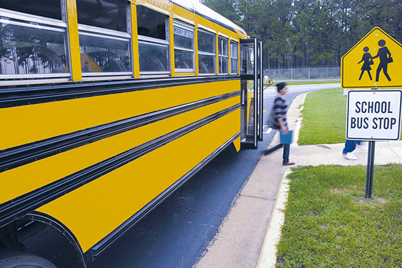 Girl leaving school bus at bus stop